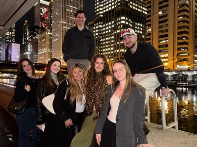 The STLN Group team together on the Chicago Riverwalk at night with the city skyline behind them
