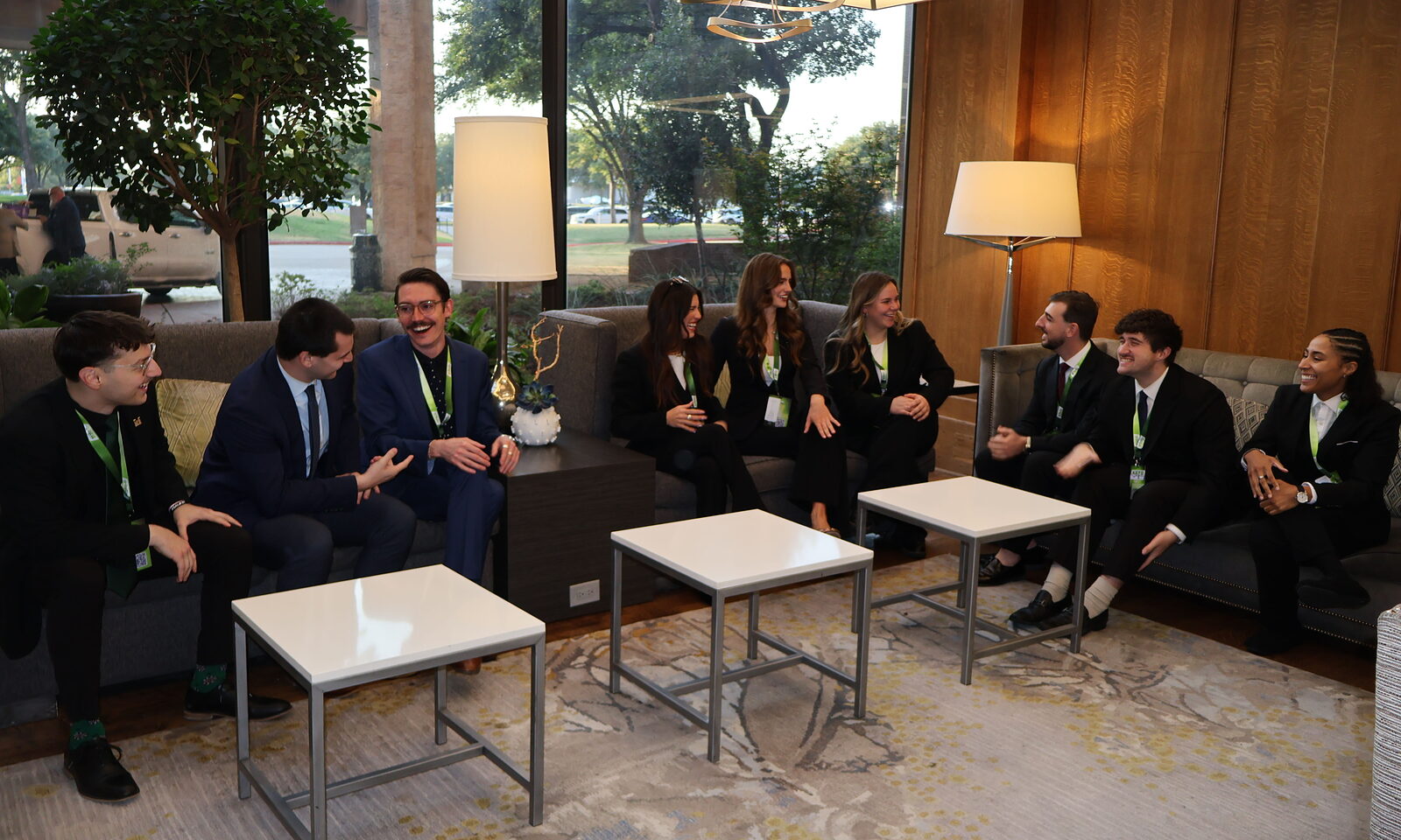 The STLN Group team in business attire, seated together and laughing in a hotel lobby lounge