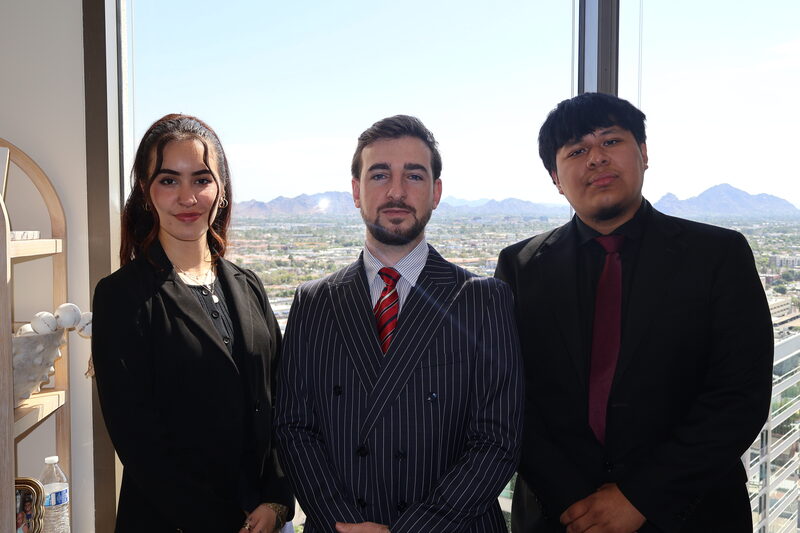 Three STLN Group team members standing together with a city skyline behind them